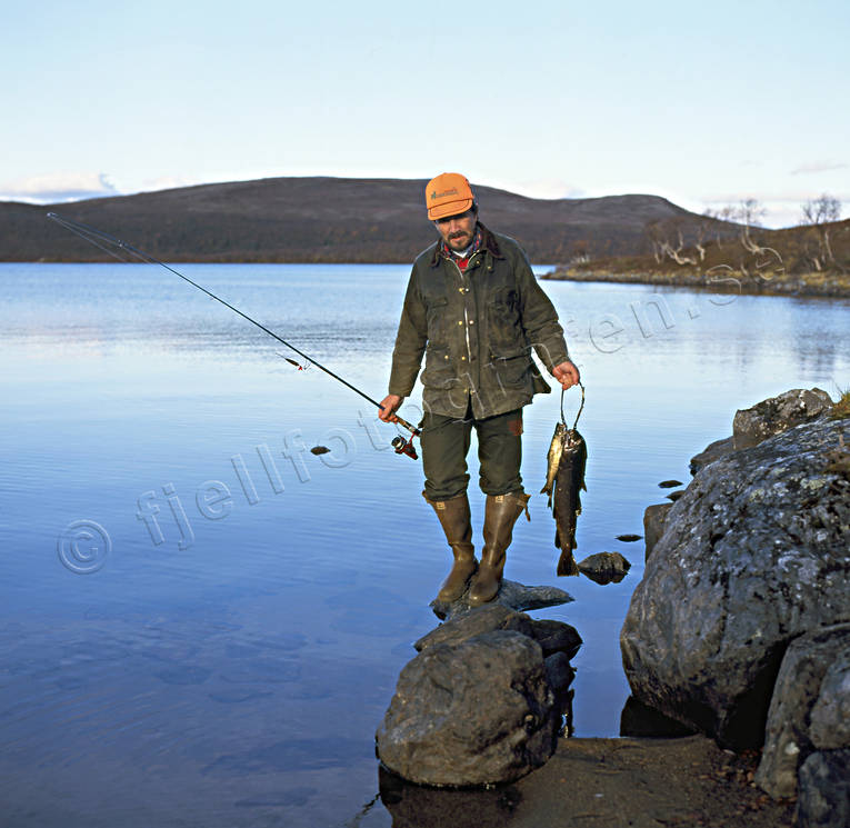 Fiskare med ett knippe öringar fiskare, fiske, fjäll, fjällfiske, fjällsjö, haspel, haspelfiske, spinn, spinnfiske, sportfiske, öring
