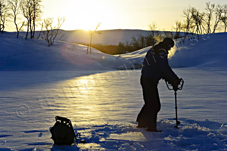 Pimpelfiskare med motorborr borra, fiske, isborr, isfiske, kallt, kyla, motljus, motorborr, pimpelfiske, sportfiske, vinter, vinterfiske